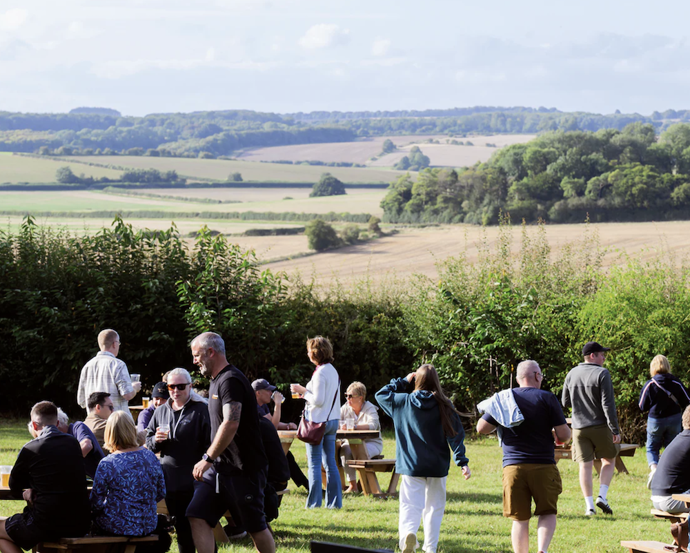 Guests in the beer garden at The Farmer's Dog with rolling Cotswolds countryside views