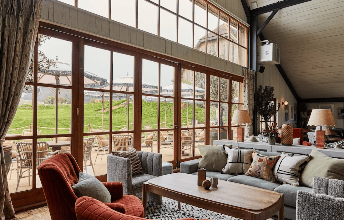 Soho Farmhouse main barn lounge with steel-framed windows and pitched timber ceiling