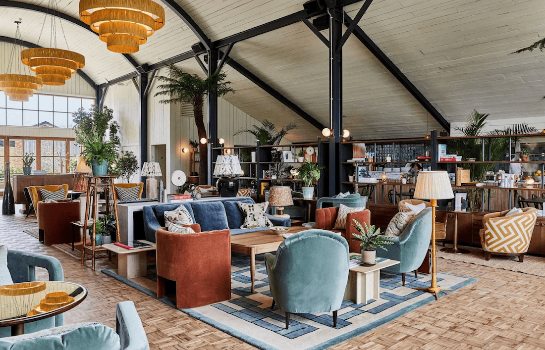 Soho Farmhouse interior with velvet armchairs, rattan chandeliers and pitched ceiling