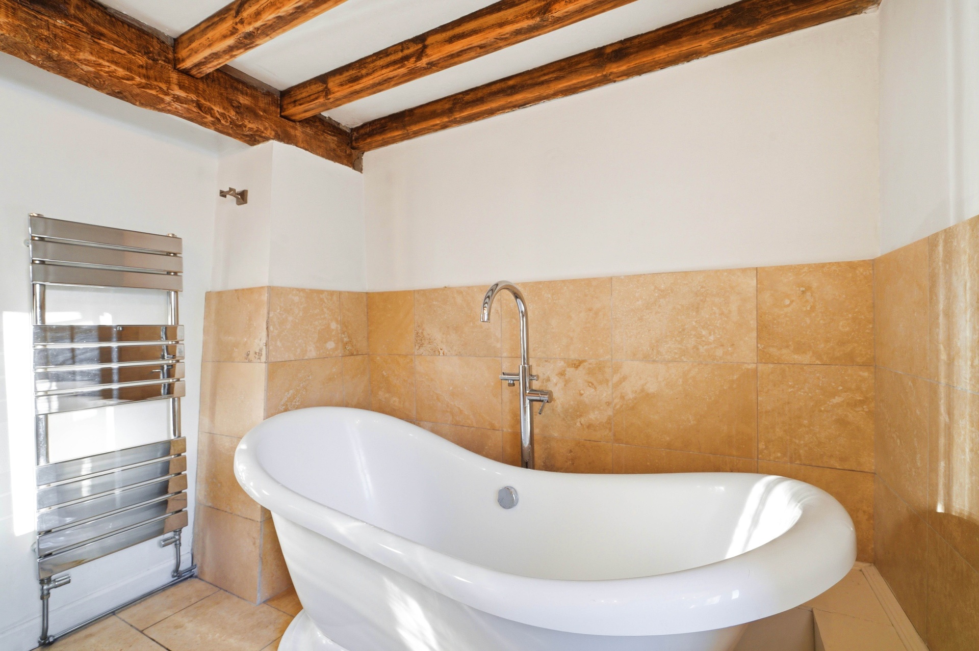 Bathroom with freestanding bath and warm stone tiles